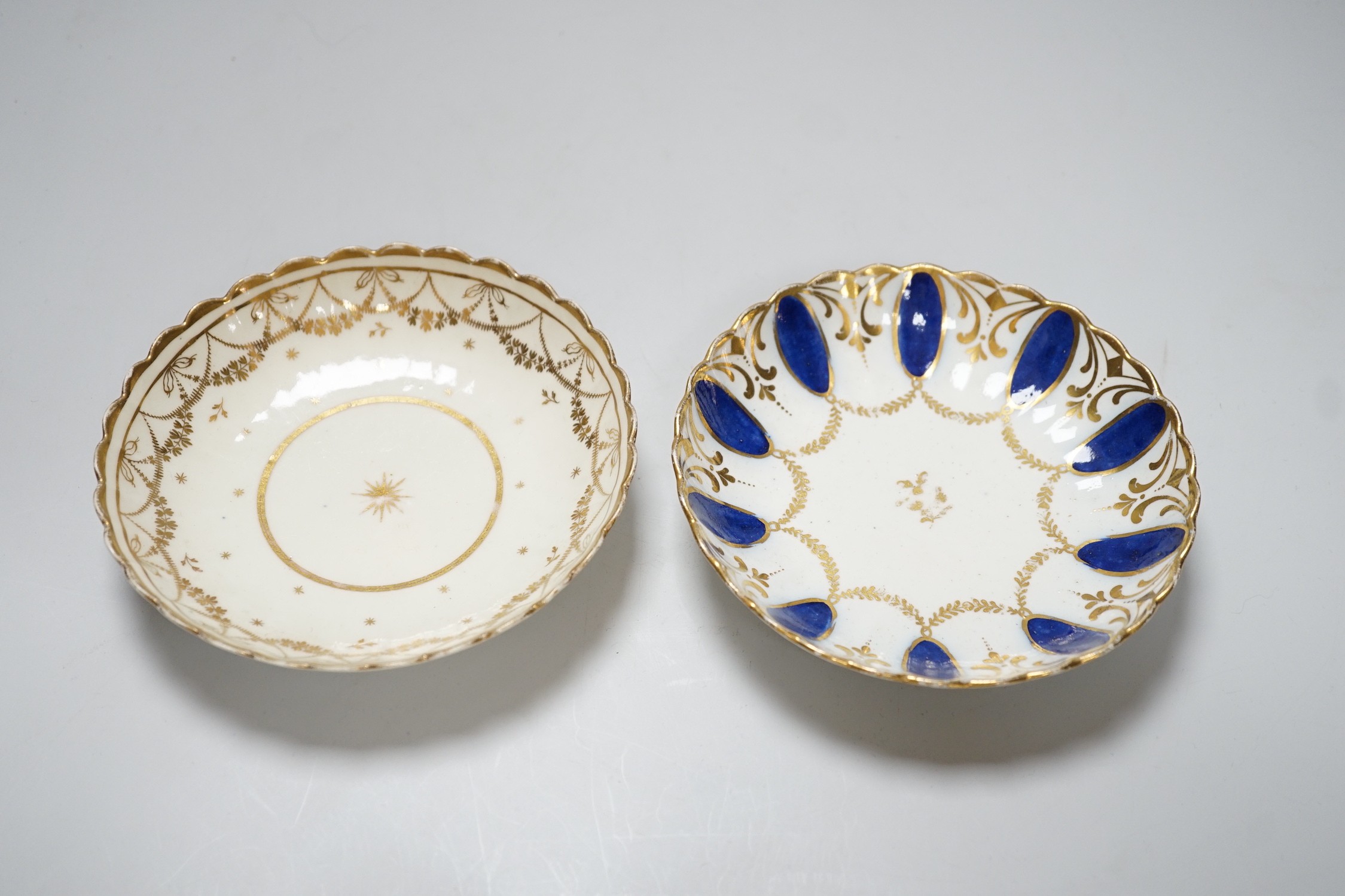 An 18th century Caughley coffee cup and saucer with blue pendants from gilt leafy swags and an 18th century Caughley coffee cup and saucer with an elaborately gilded border, both probably decorated at Chamberlains premis